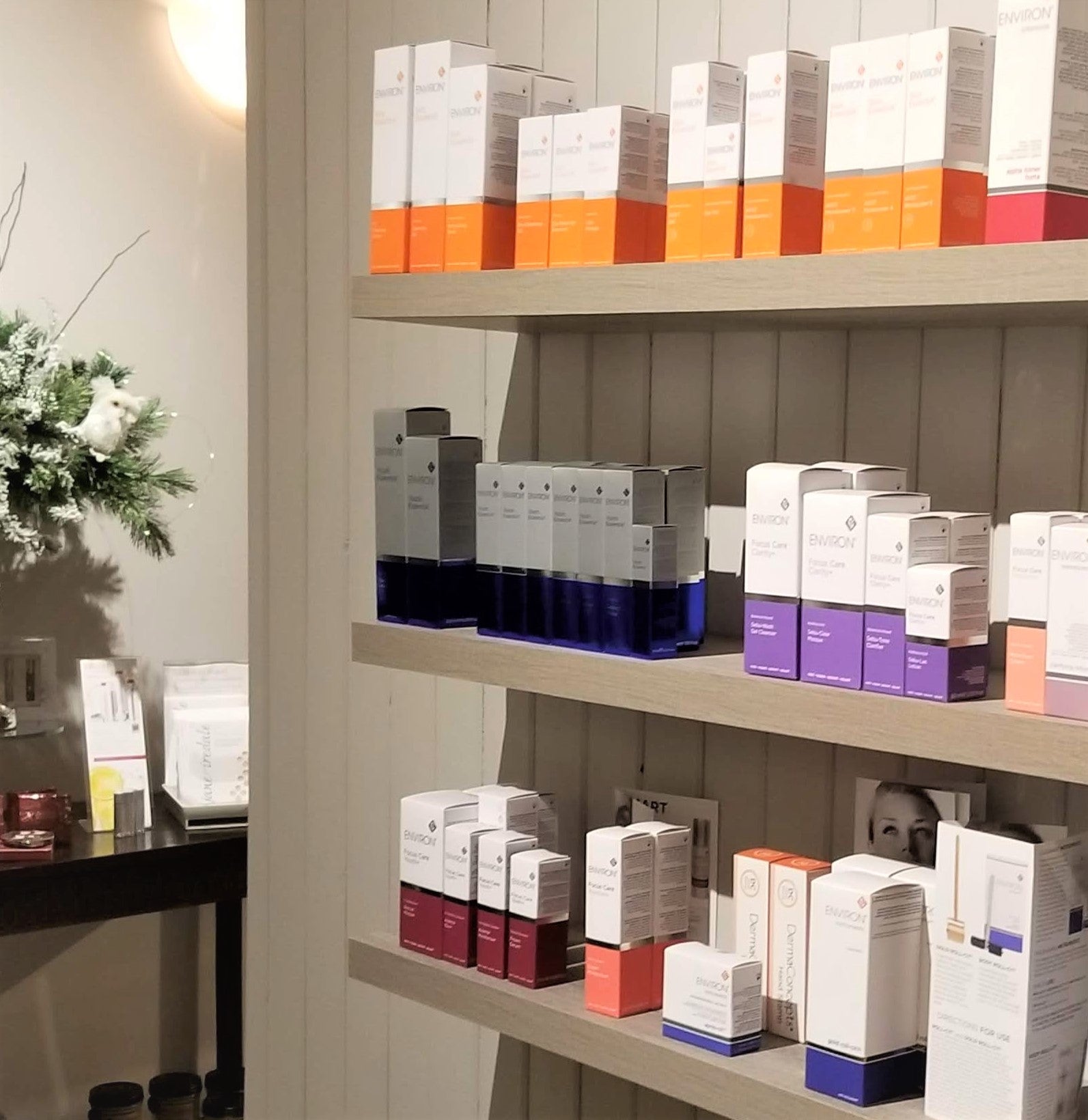 White and colored rectangular boxes of environ skincare products displayed on wooden shelves for medspa use