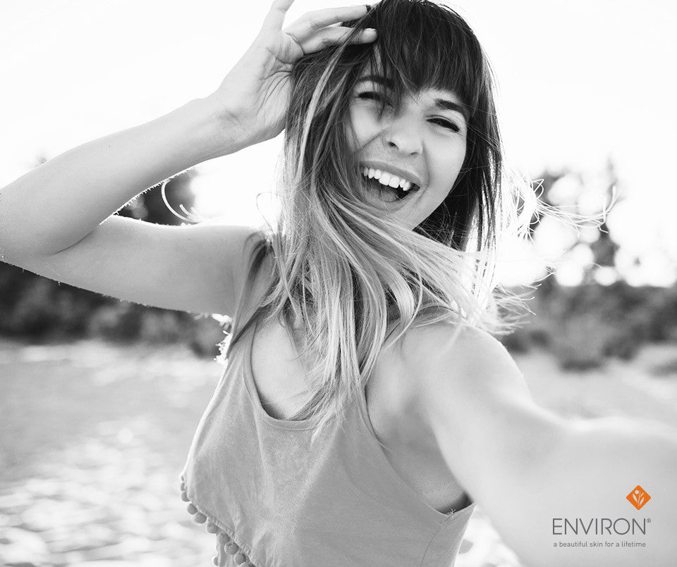 A woman with long layered hair and bangs wearing a sleeveless top with tassel trim in an article about happiness.