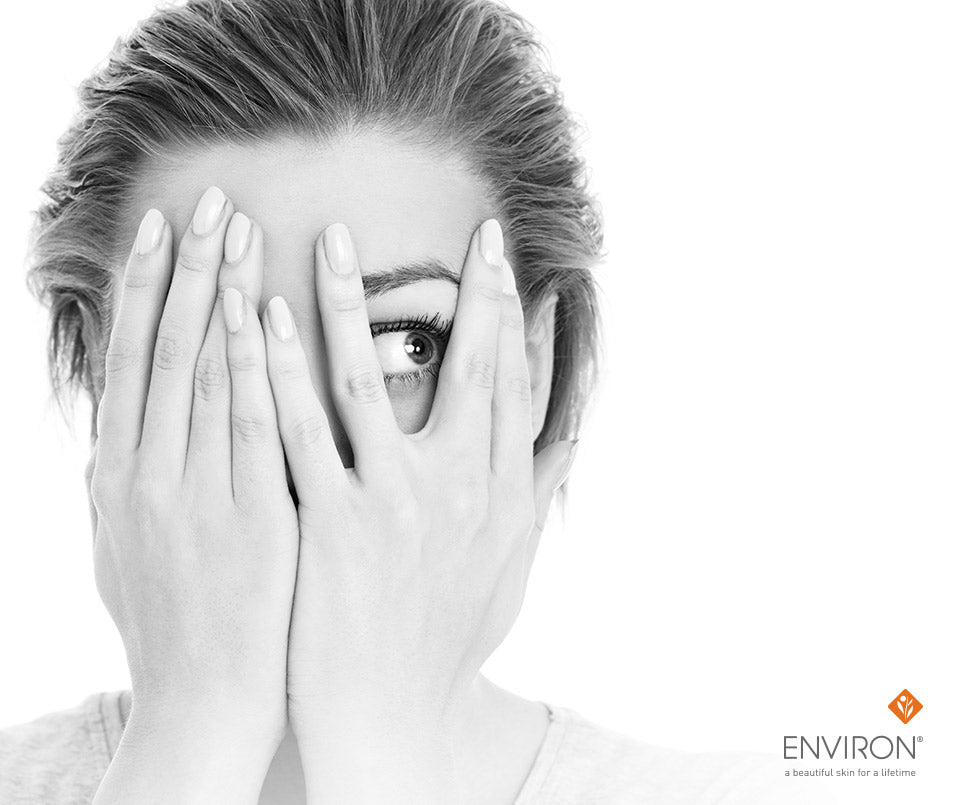 Black-and-white portrait of a woman with hands covering her face showing one eye in article about the b-active range for problem skin