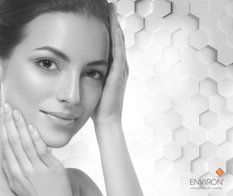 A woman with dark hair and a gentle smile cradling her face against hexagonal patterns in superior skin care article.