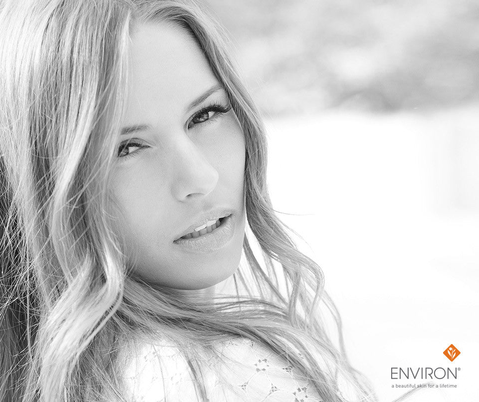 Black-and-white portrait of a woman with long wavy blonde hair and soft makeup highlighting skin essentiA benefits.