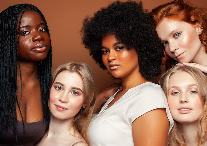 Five diverse women with varied hair textures and skin tones pose against a warm brown backdrop in identifying powerful personalities