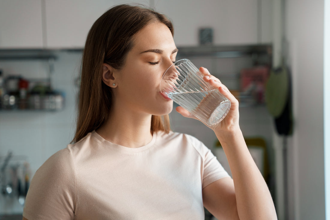 Clear ribbed glass tumbler filled with water illustrating hydration in article titled de-hydration.