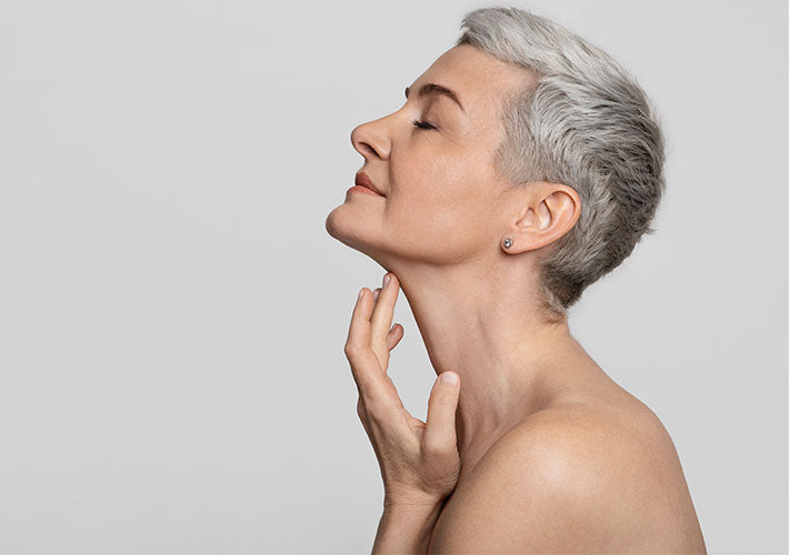 A woman with short sleek silver hair wearing a delicate diamond stud earring illustrating external effects on aging.