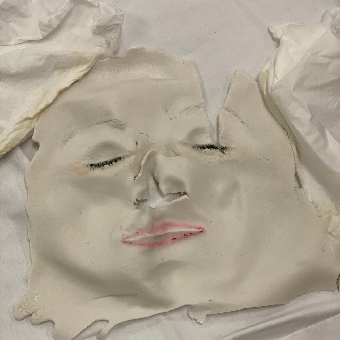 A used off-white molded facial mask with pink lips designed to refresh your summer skin