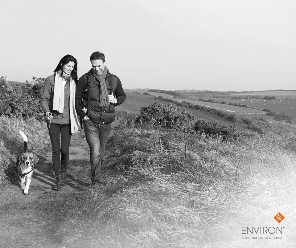Beige wool scarf worn by woman walking with man and dog along a grassy path in happy 2018 resolution success article