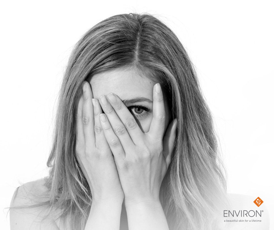 Black and white portrait of a woman with long layered hair covering her face highlighting oily complexion care tips