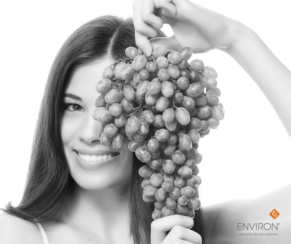 A woman holding a large dense cluster of grapes representing natural skin care in summer proof your skin article