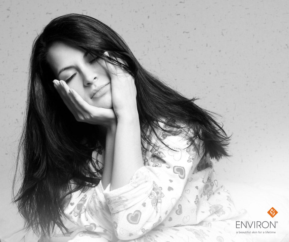 A woman with long dark hair wearing a white pajama top with heart and bear patterns in a wake up skin article.