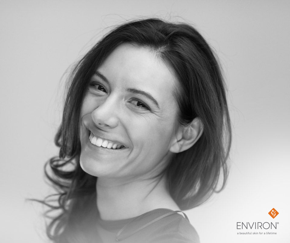 Black-and-white portrait of a smiling woman with shoulder-length dark hair in an article about fighting free radicals for radiant skin