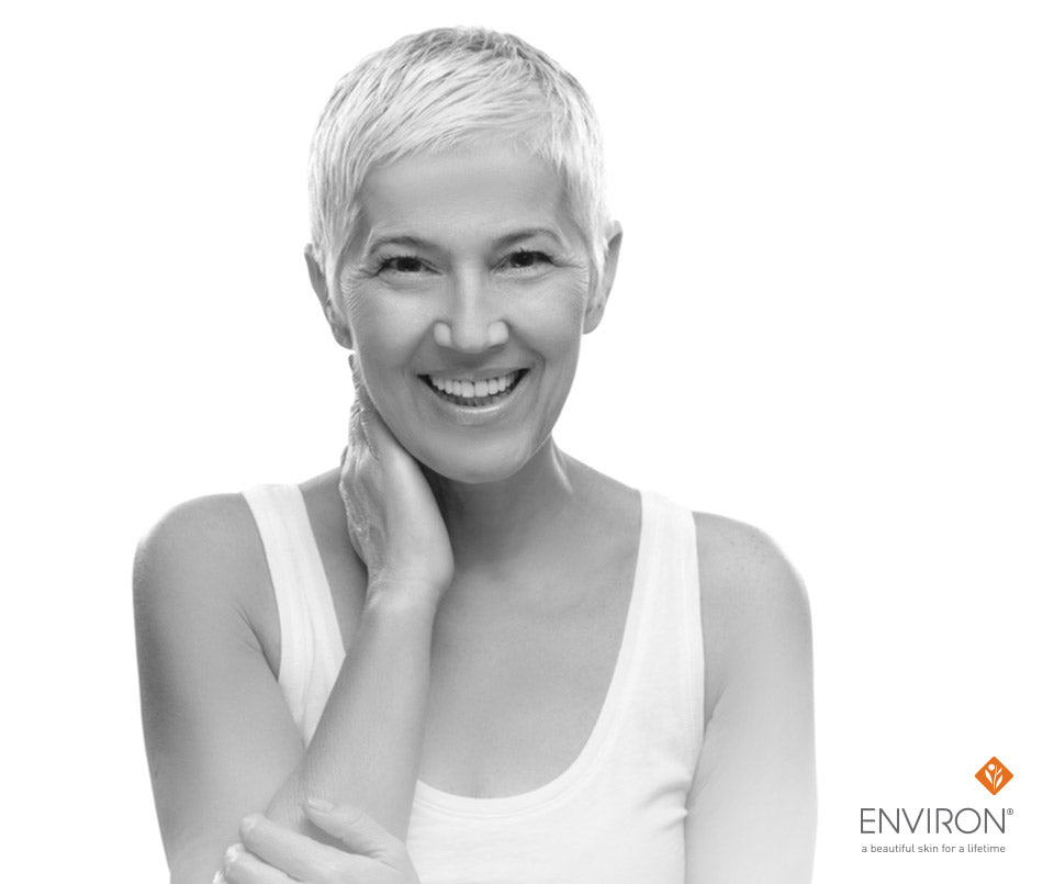 A smiling woman with short light hair wearing a simple white tank top promoting ditch dry skin tips