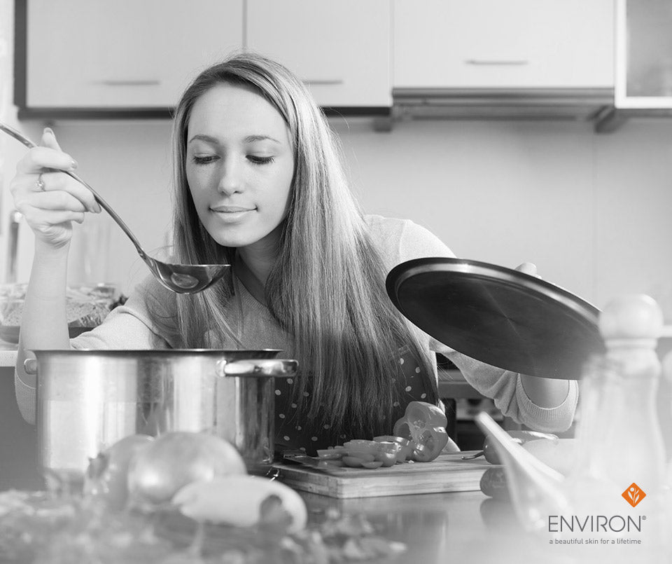 A woman lifting a pot lid and holding a ladle in a kitchen illustrating turning attitude into gratitude