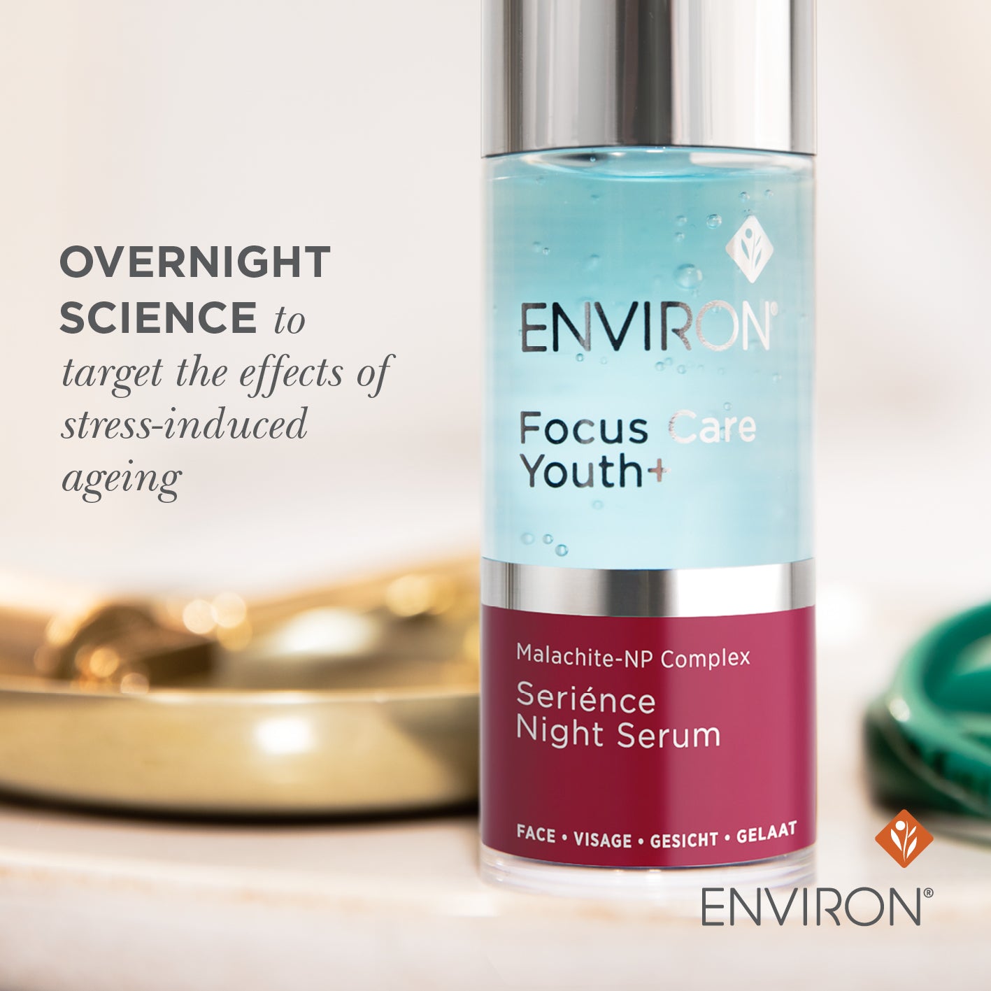 A sleek transparent glass bottle with silver cap and maroon label containing light blue environ focus care youth+ sérience night serum