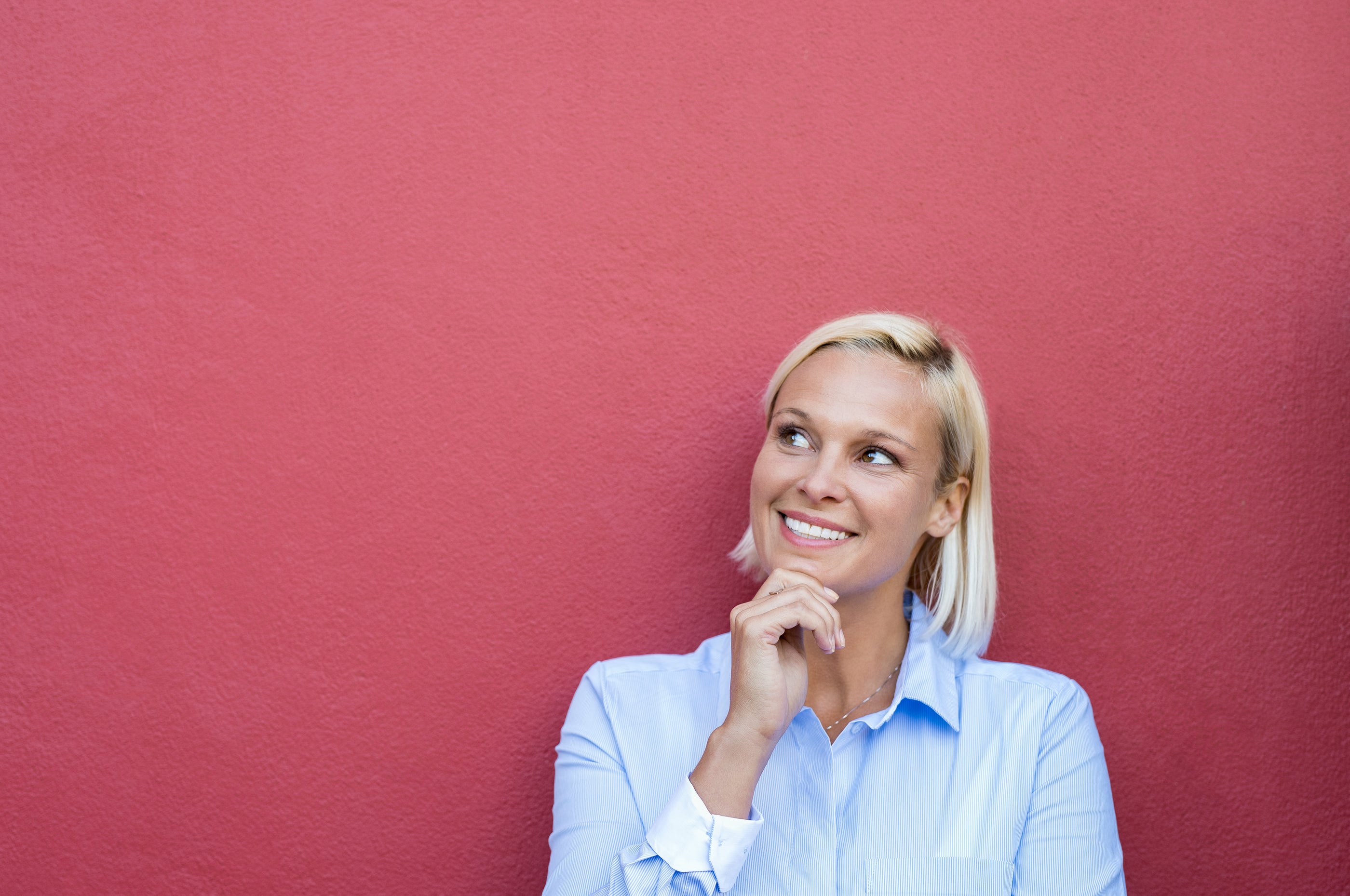 A woman with blonde hair wearing a light blue button-up shirt promoting positive attitude and beautiful skin tips.