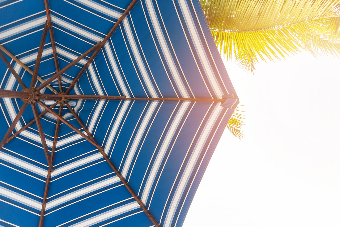 Blue and white striped patio umbrella with wooden frame providing UV protection for your skin outdoors