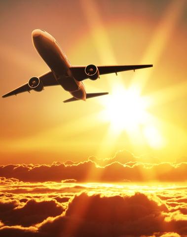 A sleek metallic airplane soars through a golden sunset sky representing jet setter inspired skin care