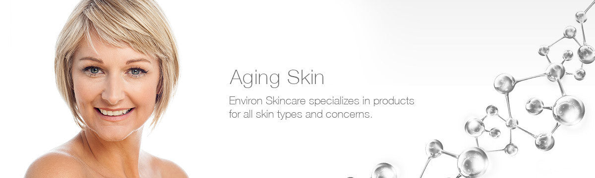 A smiling woman with short blonde hair and blue eyes wearing a simple white top in aging skin collection