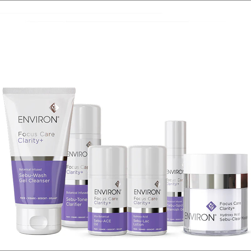 A collection of white and purple Environ Focus Care Clarity+ skincare products, featuring a gel cleanser and clear masque, stands against a plain white background.