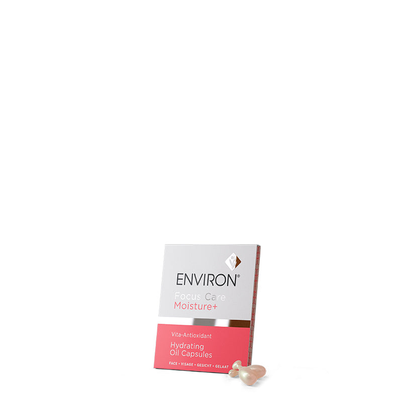 A white and pink box of Environ Focus Care Moisture+ Vita-Antioxidant Hydrating Oil Capsules sits next to individual skincare capsules on a plain background.