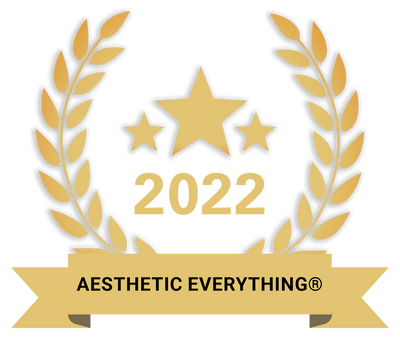 Gold laurel wreath emblem featuring three stars and the year 2022, with a ribbon banner displaying ’aesthetic everything®’.
