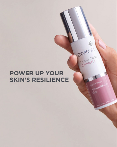 A sleek silver and white environ focus care comfort vita-enriched antioxidant gel bottle with a matte finish, held in hand.