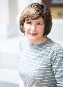 A woman with short brown hair wearing a gray and white striped long-sleeved top.