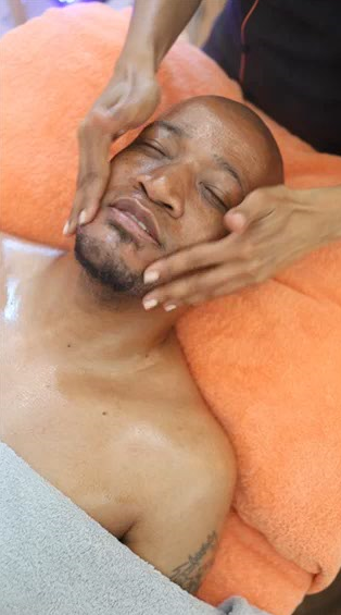 Orange towel draped over a man’s head during a facial massage.