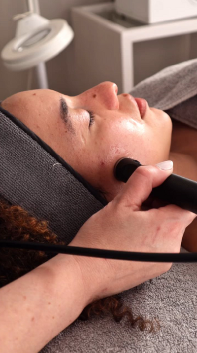 Black handheld facial device being used on a person’s face.