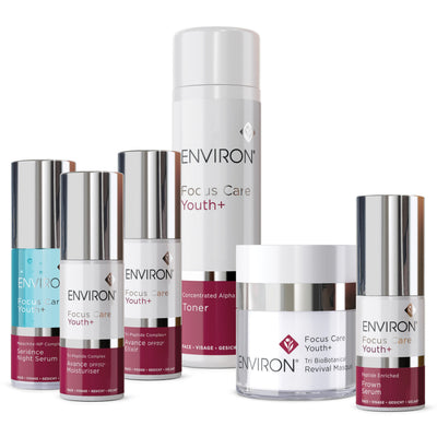 The environ focus care youth+ skincare collection features sleek, modern bottles and jars with silver caps and white labels accented by deep red bands.