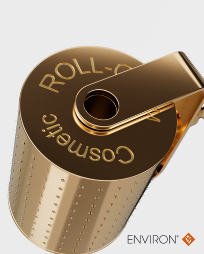 Gold-colored metallic cosmetic roller with a textured, perforated surface and engraved ’roll-o cosmetic’ branding.