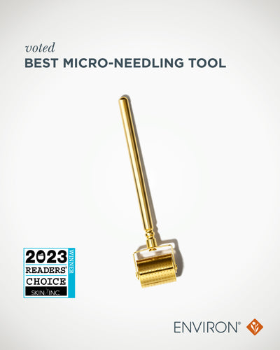 Gold-colored micro-needling roller with a sleek, cylindrical handle and a rounded head featuring evenly spaced tiny needles.