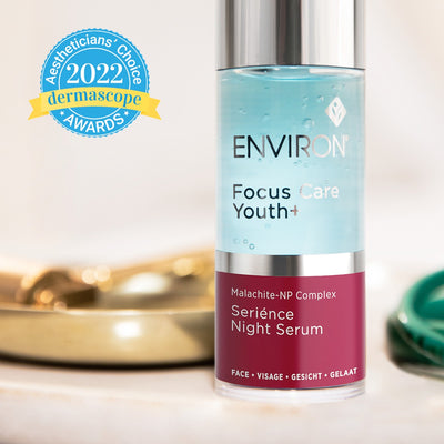 A sleek, transparent glass bottle with a silver cap and maroon label containing environ focus care youth+ serience night serum.