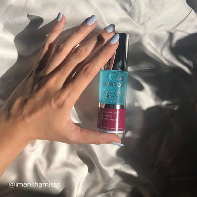 A sleek, transparent bottle with a silver cap and vibrant turquoise liquid inside, labeled ’environ focus care youth+ serence night serum,’ featuring a pink lower section.