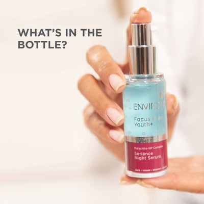 A clear glass bottle with a silver pump dispenser, featuring a light blue and maroon label that reads ’enviro focus care youth+ malachite-np complex seriènce night serum.’