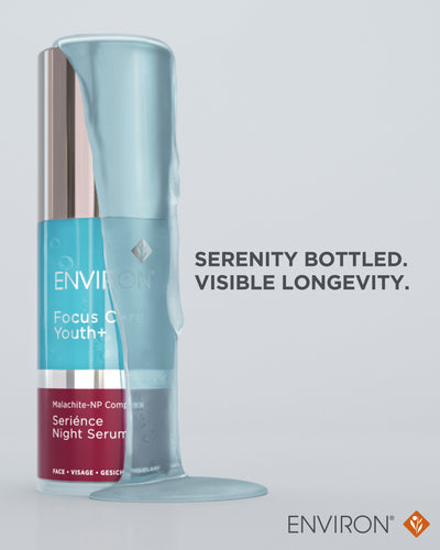 A sleek, translucent blue serum bottle with a rose gold cap and silver band, labeled ’environ focus c youth+ seriènce night serum.’