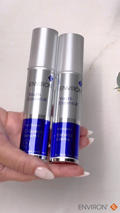 Two silver and blue environ youth essentials skincare products held in a hand.
