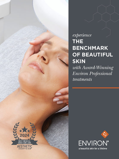 A woman with closed eyes and light pink manicured nails receives a facial treatment at an environ professional spa, her face gently cradled by hands.