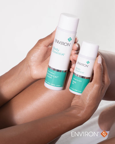 Two white cylindrical bottles with teal labels and caps, featuring the environ body essentia® line.