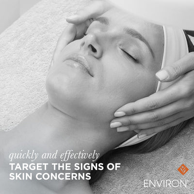 A woman receiving a facial treatment with her eyes closed and hands gently cradling her face.