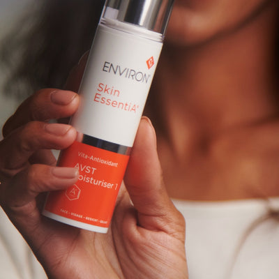 A sleek white and orange cylindrical bottle of environ skin essentia avst moisturiser 1, featuring a silver cap and bold branding.