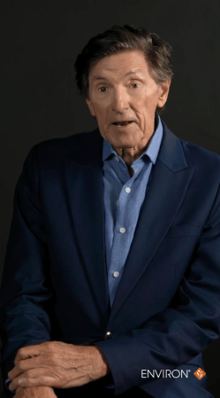A man wearing a navy blue suit jacket over a light blue button-down shirt.