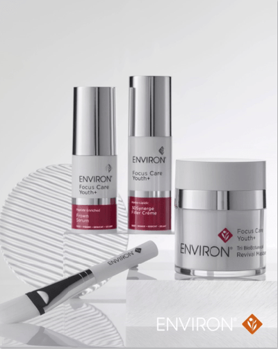 The environ focus care youth+ skincare set features sleek, silver-topped bottles and a matching jar with minimalist white labels accented by deep red bands.