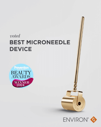 Gold-colored environ microneedle roller with a sleek, cylindrical handle and textured rolling head.