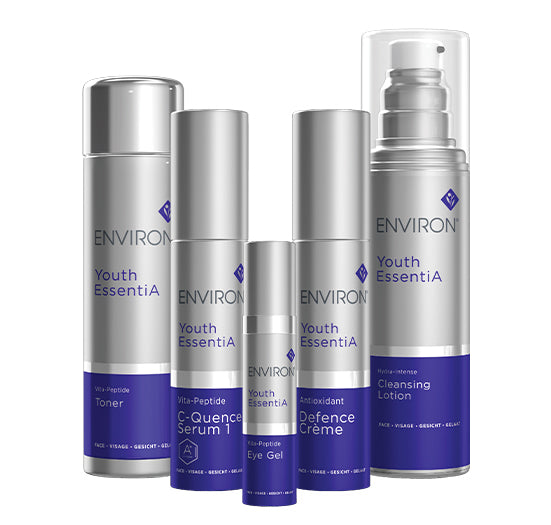 A comprehensive set of Environ Youth EssentiA skincare products showcases five silver bottles including toner, serum, eye gel, defense creme, and cleansing lotion.