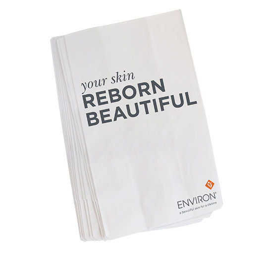 White Environ skin care paper bags feature the bold slogan "your skin REBORN BEAUTIFUL" and the brand's signature logo.