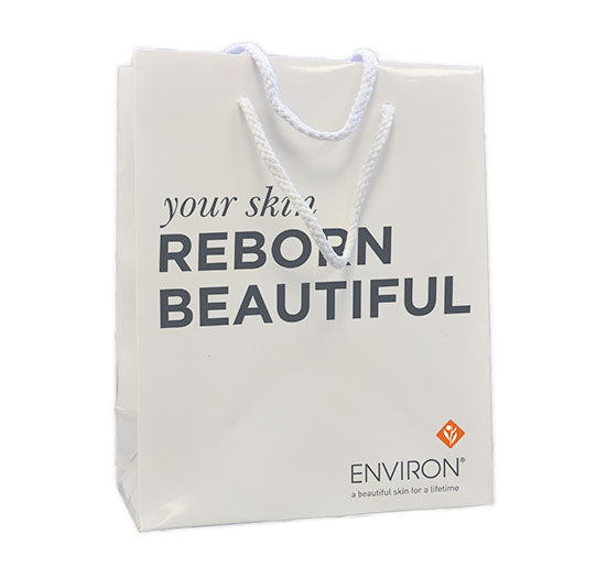 A white Environ shopping bag with braided rope handles features the brand logo and the slogan "your skin REBORN BEAUTIFUL".