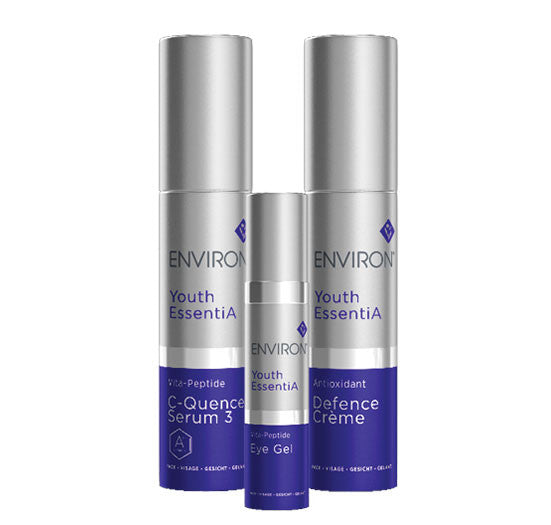 An Environ Youth EssentiA skincare collection features the Vita-Peptide C-Quence Serum 3, Eye Gel, and Antioxidant Defence Crème in tall silver and blue containers.